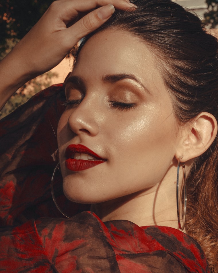 Warm portrait with a bold red lip and gold hoop earrings
